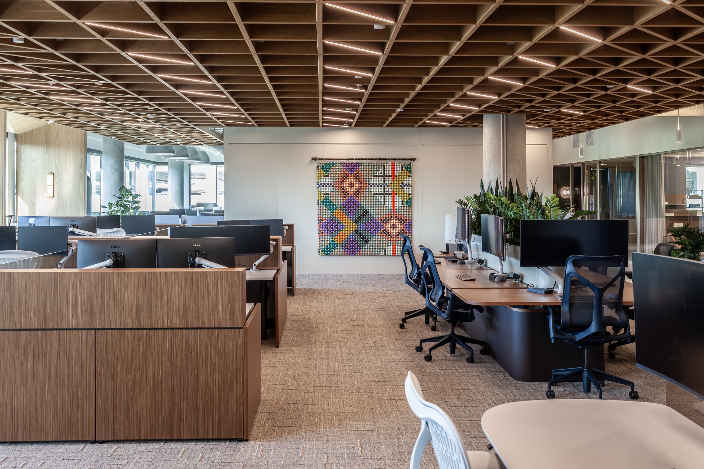 The beadwork hanging in an open office, a square of geometric color above the desks
